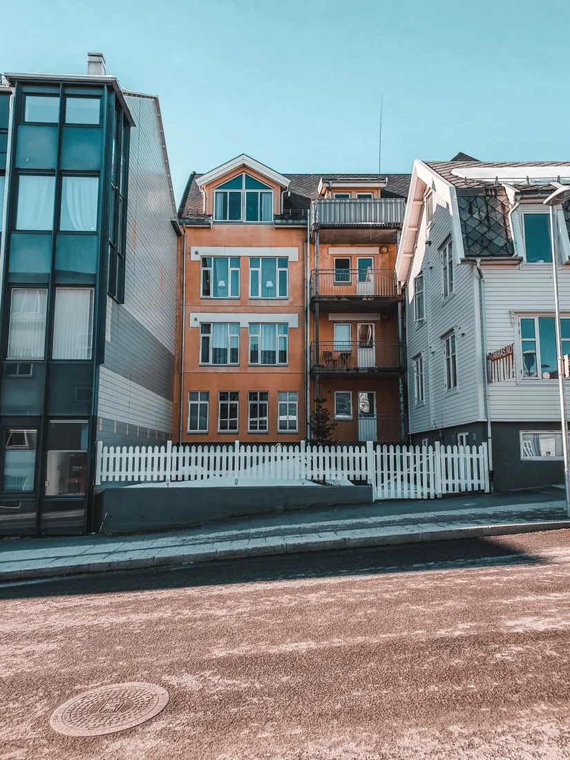 Reference photograph, not Tirumala work: orange and white urban residential buildings with bay windows and metal balcony railings.