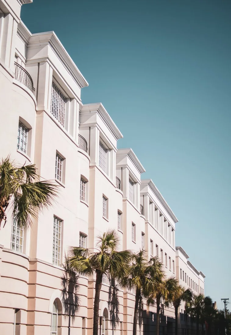 Reference photograph, not Tirumala work: pale mid-rise residential block with rows of windows and palm trees along its frontage.