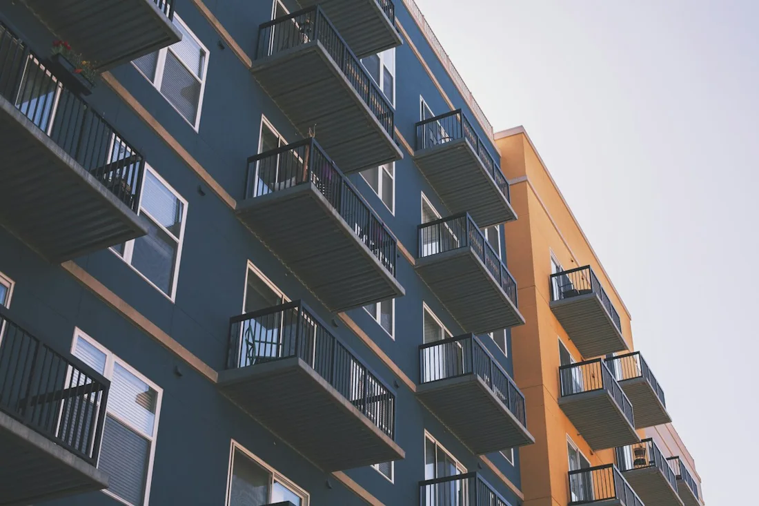 Reference photograph, not Tirumala work: dark grey apartment facade with orange accents and stacked projecting metal balconies.