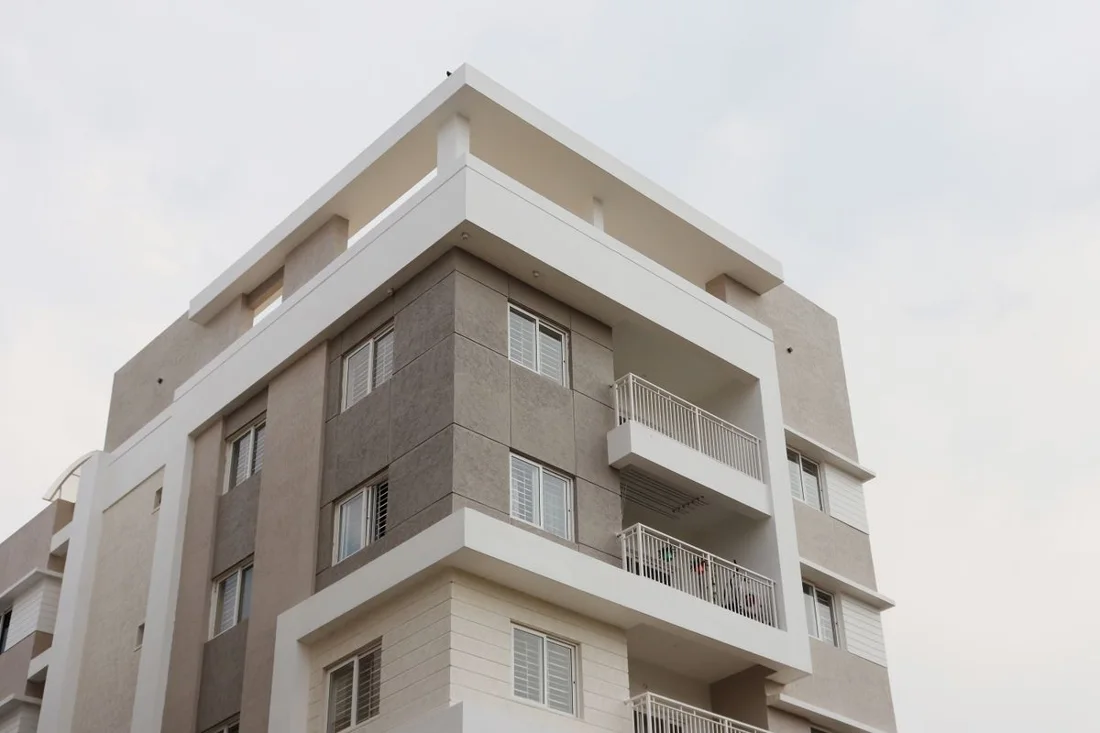 Reference photograph, not Tirumala work: white and grey stone-clad apartment building with recessed balconies and metal railings.